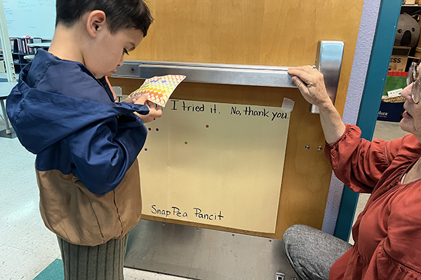 A boy chooses a sticker to put on the sheet of paper