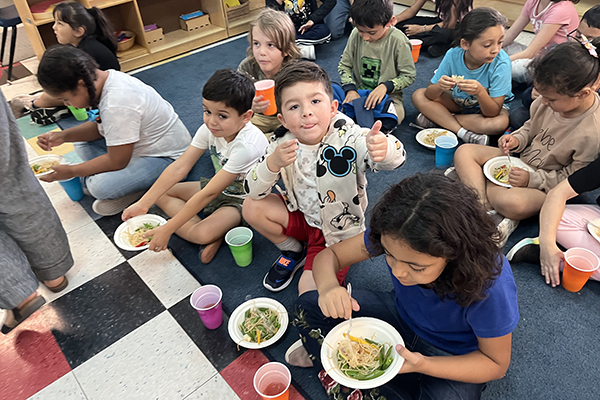 A boy gives two thumbs up for the bowl of pancit he and his classmates enjoyed