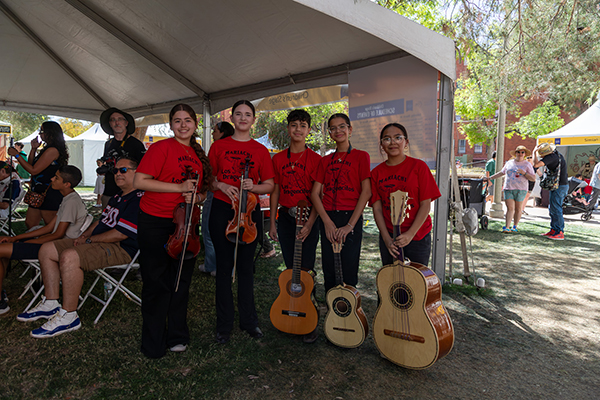Mariachi performers in red t-shirts pose with their instruments
