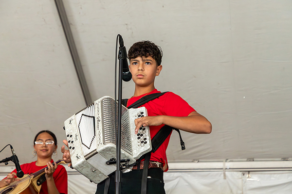 A boy plays accordion with the mariachi group