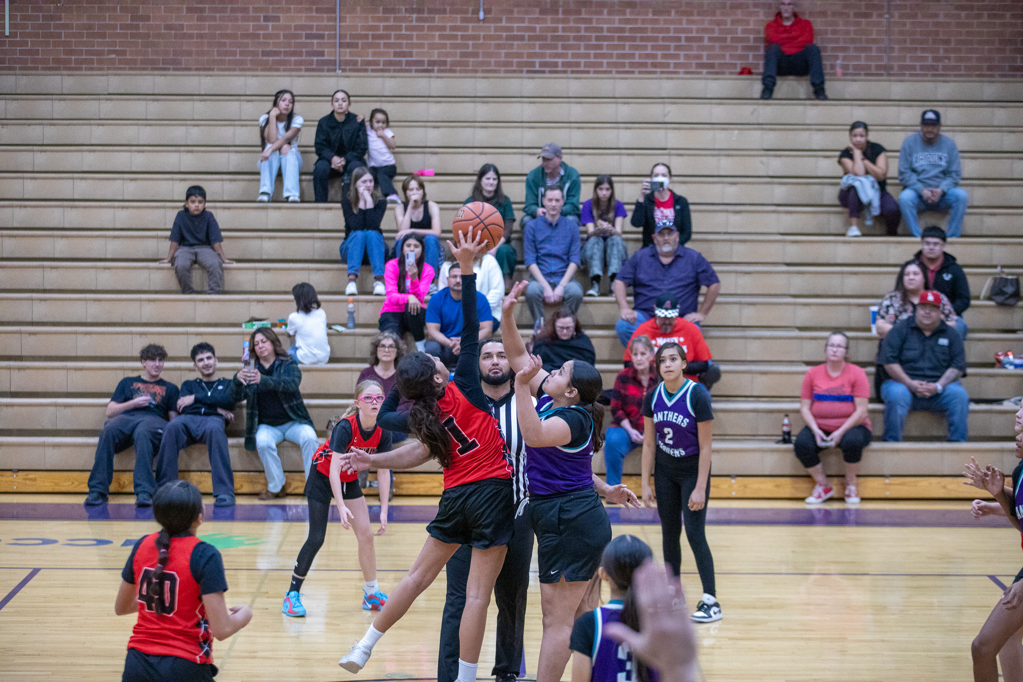 Two girls jump up for the basketball