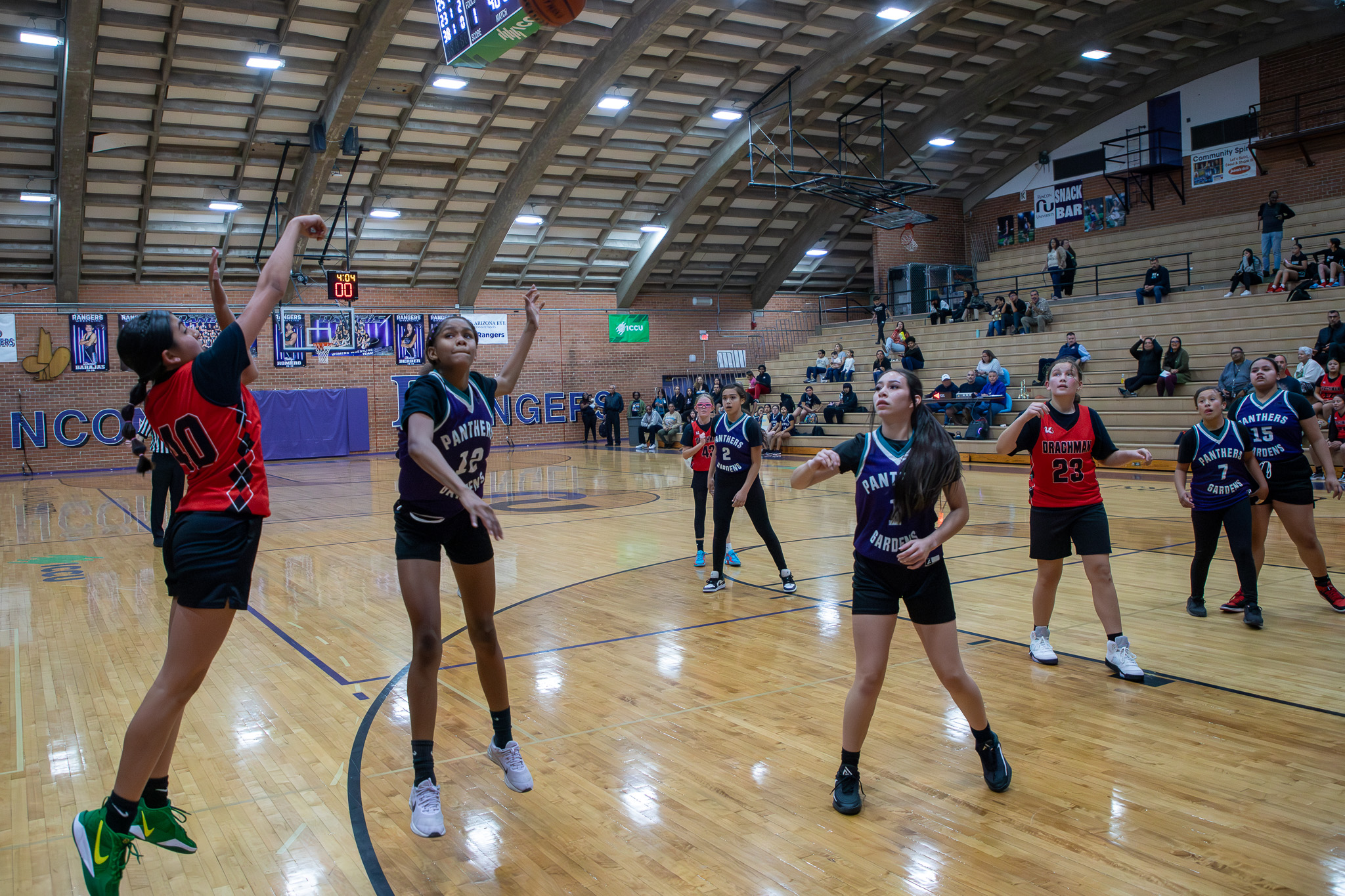 A girl in a red jersey shoots the basketball