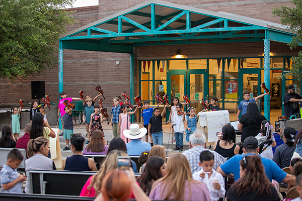 Students hold up their violins after their performance