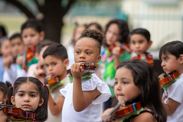 Students play violin music for their families