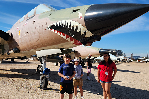 Students stand outside in front of a plane painted like a shark