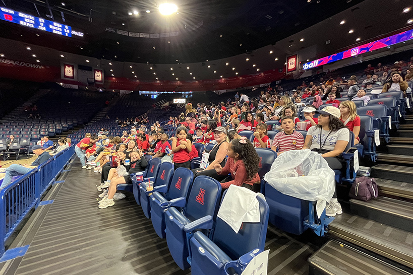 Students sitting in the stands watching the volleyball match