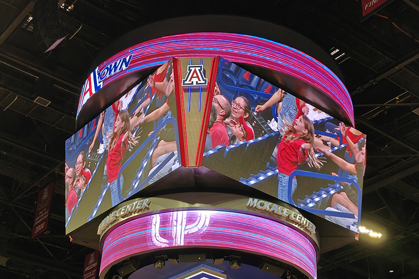 Jumbotron screens show students in the stands