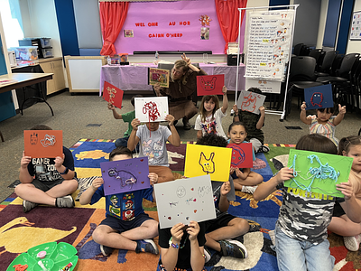 Students in the library hold up their artwork